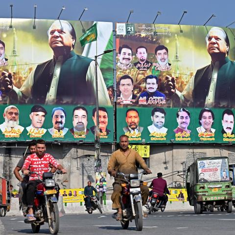 People ride past large banners of Pakistan's former Prime Minister Nawaz Sharif displayed along a street ahead of his arrival in Lahore on October 19, 2023. (Arif Ali/AFP via Getty Images)