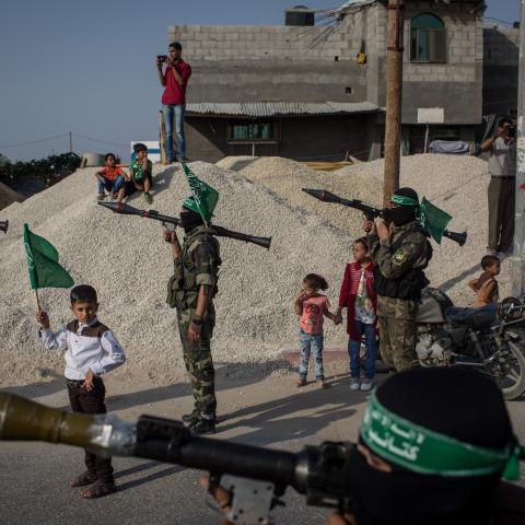 A young boy holds up a Hamas flag in between Palestinian Hamas militant during a military show in the Bani Suheila district of Gaza on July 20, 2017. (Chris McGrath via Getty Images)