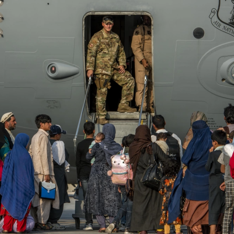 Service members prepare to board evacuees onto a C-17 Globemaster lll on Aug. 22, 2021, at Al Udeid Air Base, Qatar. ( Kylie Barrow via DVIDs) 