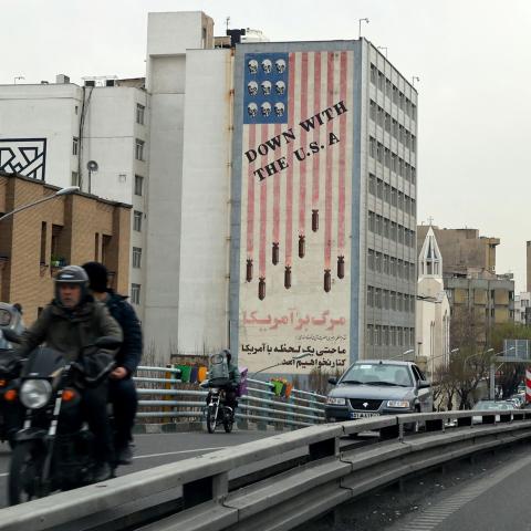 Vehicles drive on a street across from an anti-US mural in Tehran on March 12, 2022. (Photo by ATTA KENARE/AFP via Getty Images)