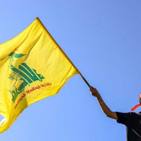 A masked demonstrator waves a flag of the Lebanese Shiite movement Hezbollah during a demonstration supporting the Palestinians in Beirut on October 20, 2023, amid the ongoing battles between Israel and the Palestinian group Hamas. (Photo by JOSEPH EID / AFP) (Photo by JOSEPH EID/AFP via Getty Images)