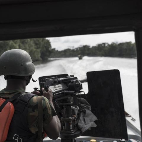 A Nigerian soldier on the back of a gun boat surveys a creek for illegal oil refineries during a patrole on April 19, 2017, in the Niger Delta region near the city of Warri. (Stefan Heunis/AFP via Getty Images)