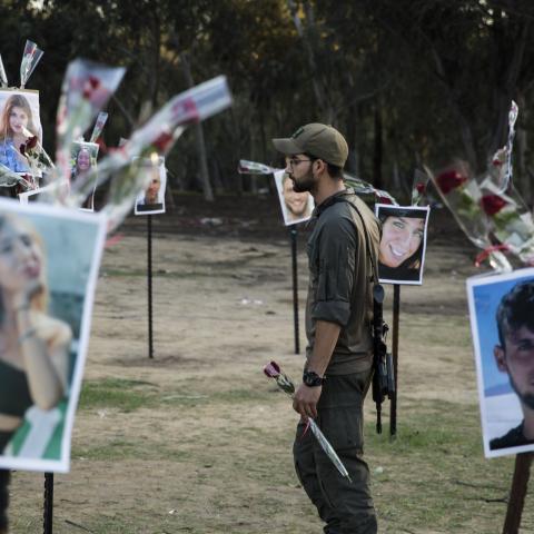 A soldier walks with a rose near photos of people killed during Hamas's attack on the Nova festival at the site on November 29, 2023, in Re'im, Israel. (Photo by Amir Levy/Getty Images)