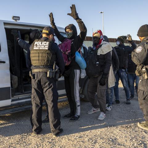 A United States Customs and Border Protection officer searches immigrants before transporting them from the US-Mexico border on December 8, 2023, in Lukeville, Arizona. (John Moore via Getty Images)