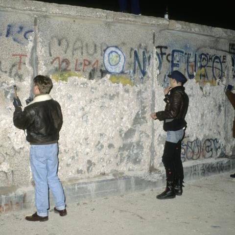 People with a chisel and sledgehammer participate in the destruction of the Berlin Wall near by the Brandenburg Gate as they celebrate the first New Year in a unified Berlin since World War II on December 31, 1989, in Berlin, Germany. (Thierry Monasse via Getty Images)