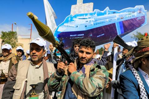 A sign depicting a cutout of the Bahamas-flagged cargo vessel Galaxy Leader, which was seized by fighters of Yemen's Huthi movement in late 2023, is raised by a protester behind a man carrying a rocket-propelled grenade (RPG) launcher during a pro-Palestinian rally in the Huthi-held capital Sanaa on February 7, 2024 amid the ongoing conflict in the Gaza Strip between Israel and the Palestinian militant group Hamas. (Photo by MOHAMMED HUWAIS / AFP) (Photo by MOHAMMED HUWAIS/AFP via Getty Images)