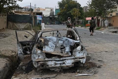 Taliban fighters stand guard near a damaged car after multiple rockets were fired in Kabul on August 30, 2021. (Photo by Wakil Kohsar/AFP via Getty Images)