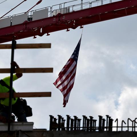 An American flag flies from a crane as a construction worker helps build a mixed-use apartment complex on January 25, 2024, in Los Angeles, California. (Photo by Mario Tama/Getty Images)