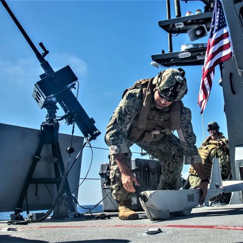 A crewman does preflight checks on an unmanned aerial vehicle (UAV) for launch aboard a MKVI patrol boat on October 16, 2019, in the Pacific Ocean. (US Navy photo by Chief Boatswain’s Mate Nelson Doromal Jr.)
