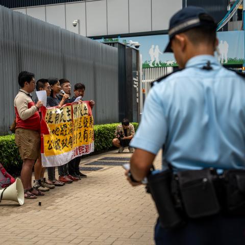A police officer looking at League of Social Democrats protesting outside the Central Government office on October 25, 2023, in Hong Kong, China. (Vernon Yuen via Getty Images)
