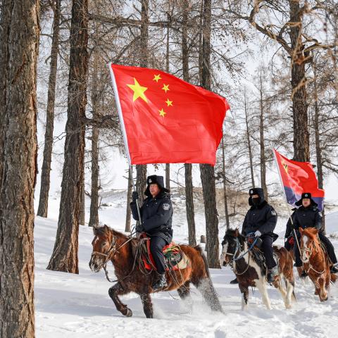 Police officers on horseback with national flags patrol the border in Xinjiang province, China, on December 29, 2023. (Costfoto/NurPhoto via Getty Images)