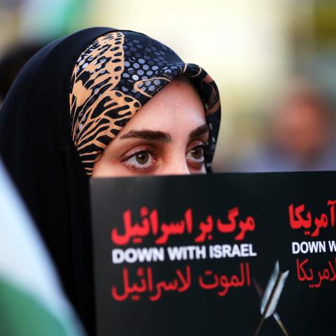 An Iranian citizen holds a placard in Tehran during a demonstration to support Iran's drone and missile attacks on Israel on April 15, 2024. (Photo by Fatemeh Bahrami/Anadolu via Getty Images)