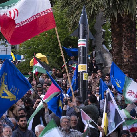 Men wave Iranian flags and flags of the Islamic Revolutionary Guard Corps at a gathering to celebrate the IRGC attack against Israel in Tehran, Iran, on April 15, 2024. (Photo by Morteza Nikoubazl/NurPhoto via Getty Images)