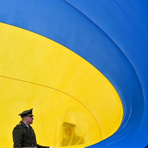 Ukrainian servicemen hold the national flag during a ceremony in Bucha, Ukraine, on March 31, 2023. (Photo by Sergei Supinsky/AFP via Getty Images)