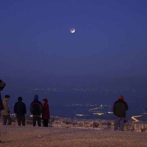 Israelis looks at a full lunar eclipse from Jerusalem’s Mount Scopus on December 10, 2011. (Menahem Kahana/AFP via Getty Images.)