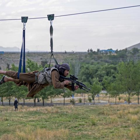 A Taliban security personnel holds his gun as he rides zipline on the outskirts of Kabul on July 4, 2024. (Wakil Kohsar/AFP via Getty Images)
