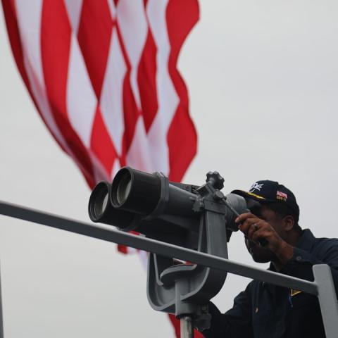 Cmdr. Roosevelt White Jr looks through the “big eyes” on the bridge wing on June 11, 2024. (DVIDS)