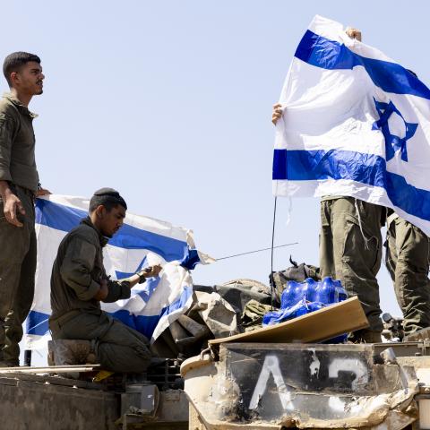 Israeli soldiers hang flags on an armored personnel carrier near the Gaza Strip border on June 6, 2024. (Amir Levy via Getty Images)