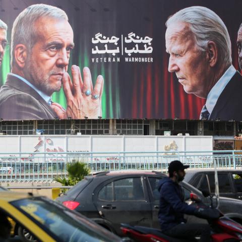Commuters drive past a billboard bearing pictures of Masoud Pezeshkian, Mohammad Bagheri, and Benjamin Netanyahu in Tehran on October 27, 2024. (Atta Kenare via Getty Images)