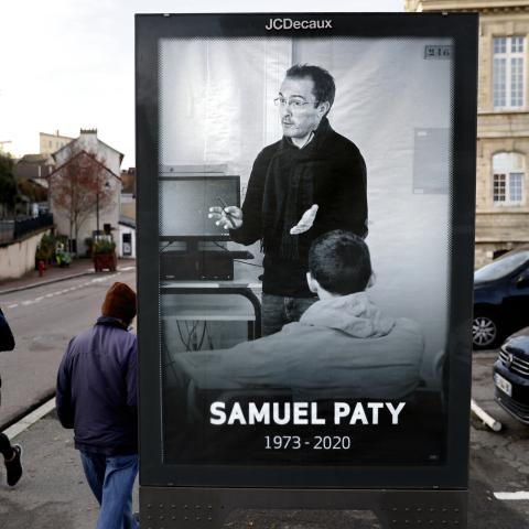 Pedestrians pass by a poster depicting French teacher Samuel Paty in Paris on November 3, 2020. (Thomas Coex/AFP via Getty Images)