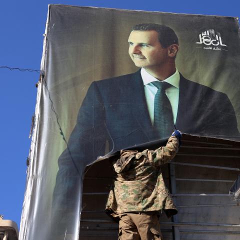 An anti-government fighter tears down a picture of Syrian President Bashar al-Assad in Aleppo, Syria, on November 30. (Mohammed al-Rifai via Getty Images)
