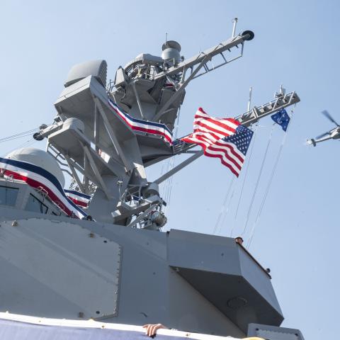 U.S. Navy Sailors with Arleigh Burke-class guided missile destroyer USS John Basilone (DDG 122), climb the brow as U.S. Marine Corps helicopters with Marine Aircraft Group 49, fly over during a commissioning ceremony on Nov. 9, 2024 at New York, New York. 