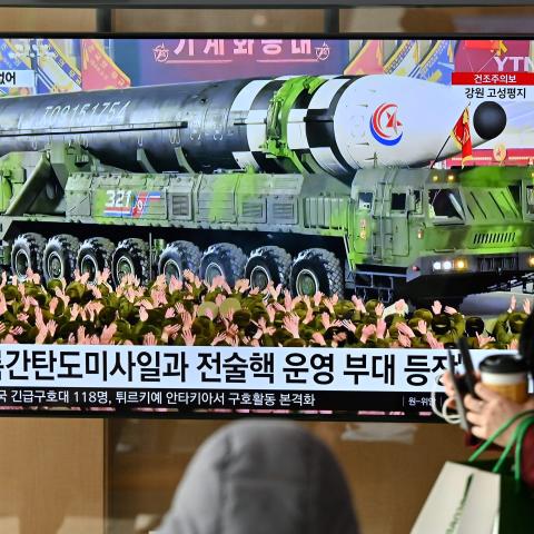 A woman walks past a television screen showing a news broadcast of a North Korean military parade showcasing a record number of nuclear and intercontinental ballistic missiles in Seoul on February 9, 2023. (Jung Yeon-je/AFP via Getty Images)