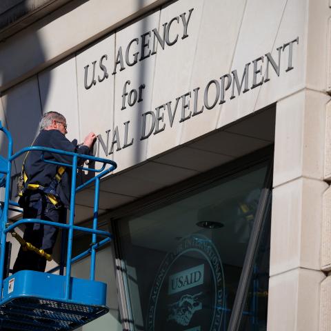 A worker removes the United States Agency for International Development sign on their headquarters on February 7, 2025, in Washington, DC. (Kayla Bartkowski via Getty Images)