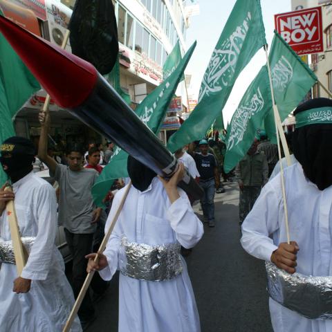 Masked Palestinian youths dressed as suicide bombers carry Hamas flags and a makeshift Qassam rocket during a rally organized by Hamas, in the West Bank City of Ramallah, on September 22, 2005 (Jamal Aruri/AFP via Getty Images)