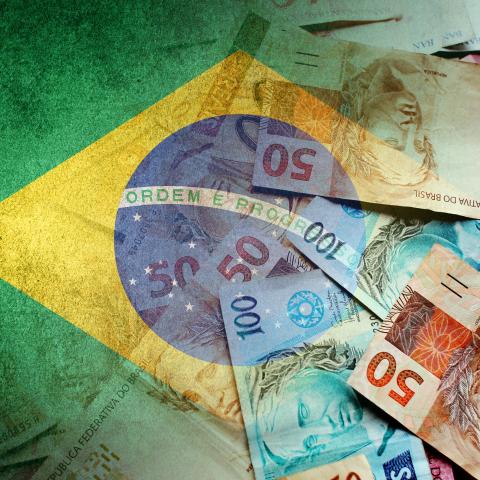 Brazilian reais cash bills and the flag of Brazil. (Getty Images)