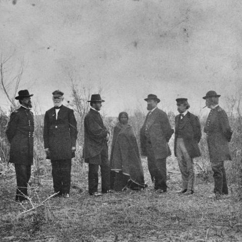 Members of the Peace Commission pose on either side of a Native American woman, wrapped in a blanket, during negotiations for the Treaty of Fort Laramie, at Fort Laramie, Wyoming, in 1868. (Alexander Gardner via Getty Images)