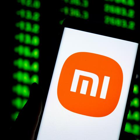 An illustration shows the Xiaomi logo displayed on a smartphone with the stock price chart in background in Chongqing, China, on April 1, 2025. (CFOTO/Future Publishing via Getty Images)