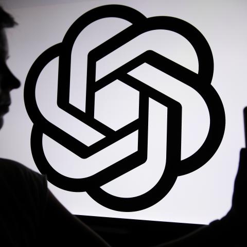 The ChatGPT logo appears with a person in front of it. (Klaudia Radecka via Getty Images)