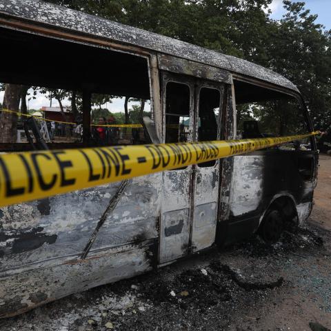 A police officer walks beside a burnt prison vehicle in Abuja, Nigeria, on July 6, 2022, after suspected Boko Haram gunmen attacked the Kuje Medium Prison. (Kola Sulaimon via Getty Images)