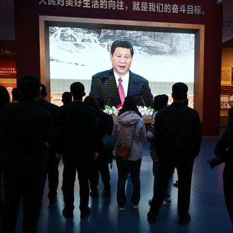 People walk past a video screen showing a speech by Chinese President Xi Jinping at the Museum of the Communist Party of China in Beijing on March 3, 2023. (Greg Baker via Getty Images)