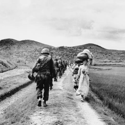 As US infantrymen march into the Naktong River region, they pass a line of refugees on August 11, 1950. (Getty Images)