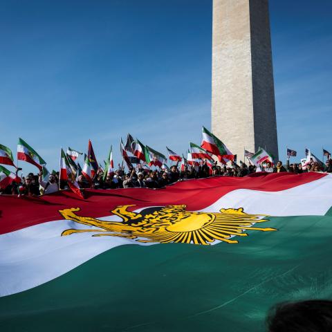 Caption Demonstrators hold a large Iranian flag dating from before the 1979 Islamic revolution during a march in support of the people of Iran in Washington, DC, on February 14, 2026. (Getty Images) 