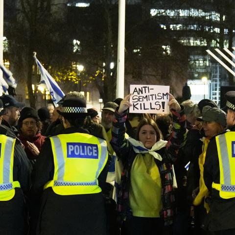A woman holds up a sign that reads "anti-semitism kills" between police officers as people take part in a Hanukkah candle-lighting in central London on December 15, 2025. (Getty Images)