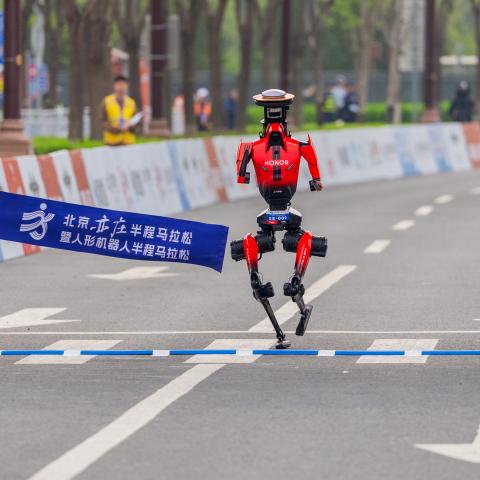 : Honor's "Lightning" humanoid robot from team Qitian Dasheng (Great Sage) crosses the finish line during the Beijing humanoid robot half marathon, on April 19, 2026 in Beijing, China. Completing the race with a net time of 50 minutes and 26 seconds, the champion robot showcased an impressive performance, beating the human half marathon record of 57 minutes and 20 seconds. (Photo by VCG/VCG via Getty Images)