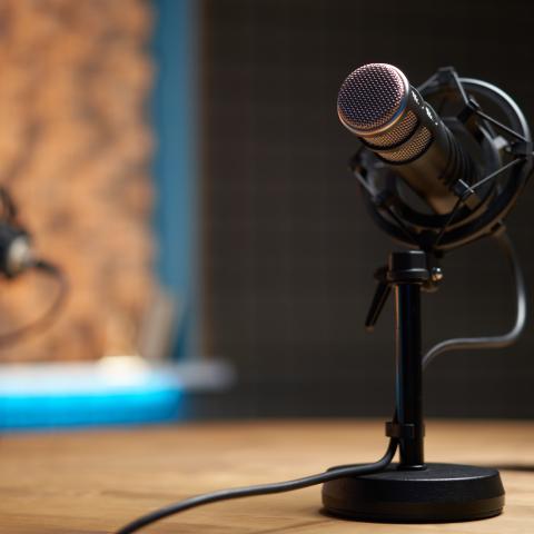 A microphone on a wooden table in a recording studio during a podcast. (Getty Stock Photo)