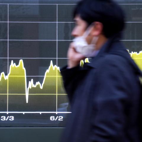 A man walks past an electronic board displaying the movement of 10-year government bonds in Tokyo on December 22, 2025. (Getty Images)