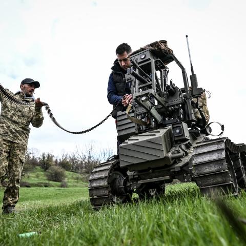 A soldier and a design engineer load a machine gun mounted on a ground robotic complex during trials at a training ground on April 10, 2026. (Getty Images) 