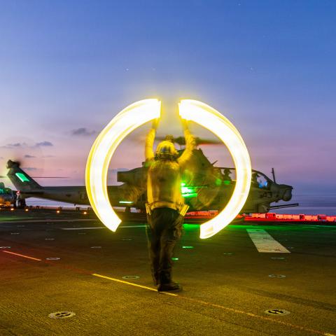 A US sailor assigned to Wasp-class amphibious assault ship USS Boxer signals an AH-1Z Viper to take off during flight operations in the South China Sea on June 13, 2026. (US Marine Corps)