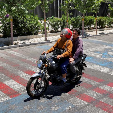 Caption A man rides a scooter along a road painted in the colours of the US and Israeli flags, in Tehran on May 26, 2026. (Getty Images) Share to Twitter