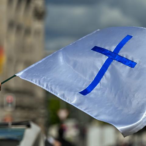 An activist holds a Bible and a blue cross on the Christian flag outside the Brandenburg Gate in Berlin, Germany, on September 6, 2025. (Getty Images)