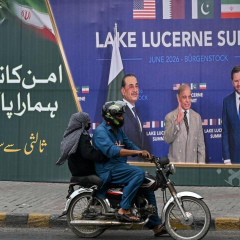 A family rides past a billboard featuring Pakistan’s Prime Minister Shehbaz Sharif, Pakistan’s Chief of Army Staff Field Marshal Asim Munir, and US Vice President JD Vance at the Lake Lucerne summit in Switzerland on July 7, 2026. (Getty Images)