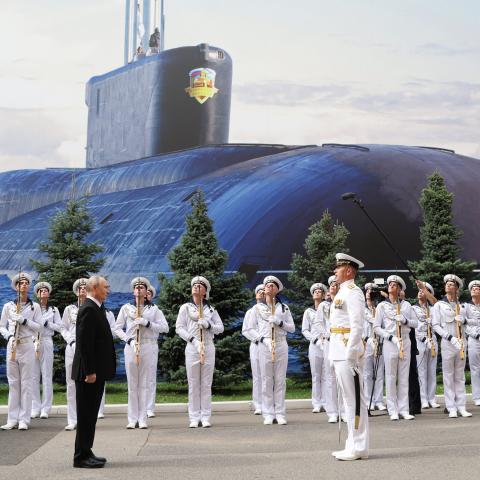 Vladimir Putin attends a ceremony to mark Navy Day at the Main Admiralty in Saint Petersburg on July 26, 2026, in front of a large photo of a submarine. (Getty Images)