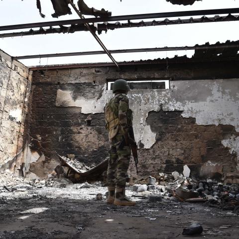 A soldier stands at a damaged house in Bosso military camp on June 17, 2016, following attacks by Boko Haram fighters. (Getty Images)