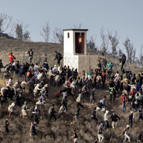 Migrants storm a barbed-wire fence as they attempt to cross the land border with Spain's African enclave of Ceuta near Fnideq in northern Morocco on September 15, 2024. (Photo by AFP) (Photo by -/AFP via Getty Images)