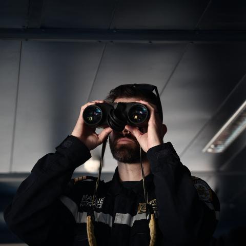 A member of the French Navy observes through his binoculars from the command post before the departure of an amphibious helicopter carrier in Toulon on February 17, 2026. (Getty Images)